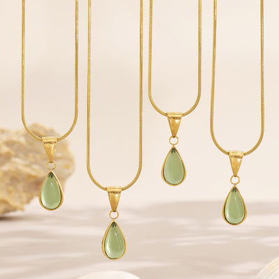 Several gold teardrop green glass pendants hanging on snake chains