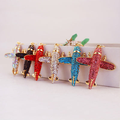 Six rhinestone airplane charms in iridescent, black, red, white, blue and pink colors.