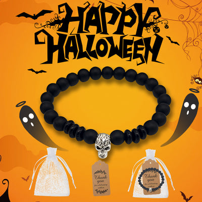 Black skull bead bracelet shown with a white drawstring pouch and thank-you tag on a Halloween background.