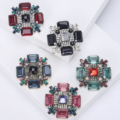 Five square crystal pearl cluster brooches in assorted colors on white blocks