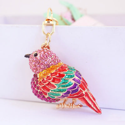 Pink rhinestone bird with multicolor feather details and a gold-tone swivel clasp.