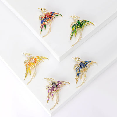 A gold-tone phoenix with sweeping crystal-set wings and tail shown on a white background