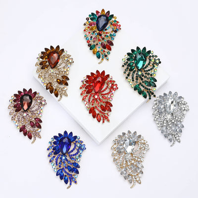 Front view of the oval gem feather brooch in eight colorways with polished metal detail on a white background
