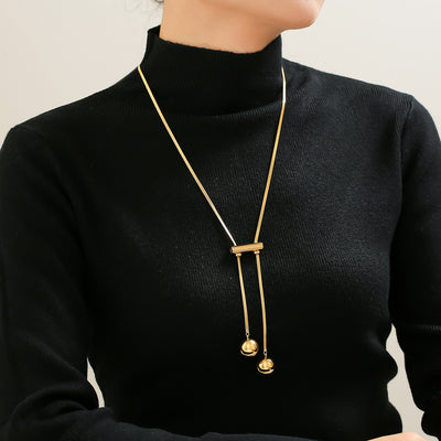 Model in black turtleneck wearing gold dual-ball lariat necklace
