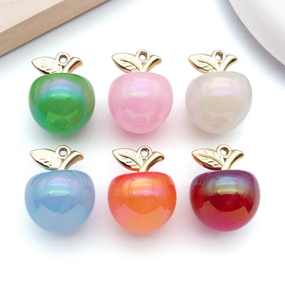 Iridescent apple charms arranged on a light background