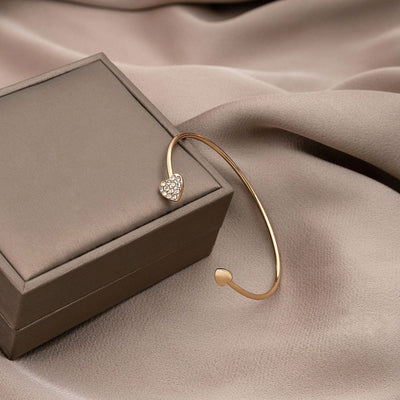Gold heart cuff resting on gray gift box