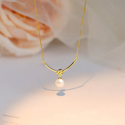 Gold open bar knot faux pearl pendant necklace soft rose backdrop