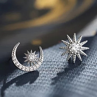 Silver asymmetric crescent moon and star studs on dark fabric