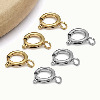 Gold-tone spring clasp jewelry findings arranged on a light background