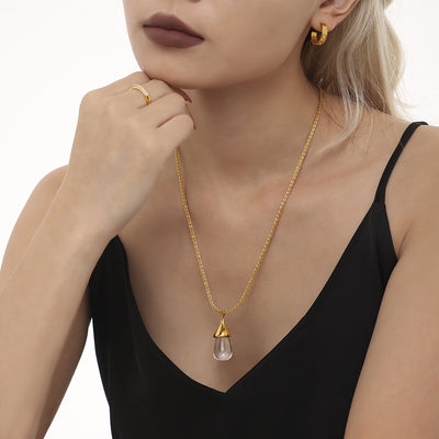 Model wearing gold clear resin drop pendant necklace black top