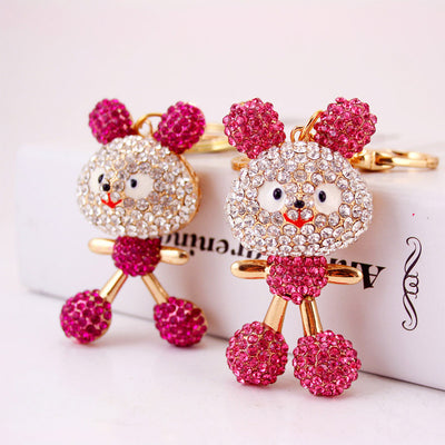 Two pink rhinestone mouse keychains standing beside a white box.