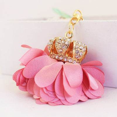 Angled close-up of the pink layered flower beneath a clear rhinestone crown