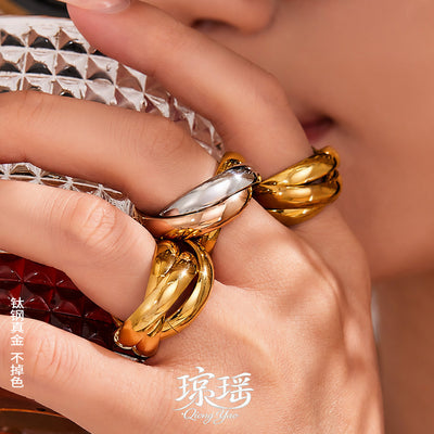 Hand wearing stacked gold and tricolor triple interlocked band rings