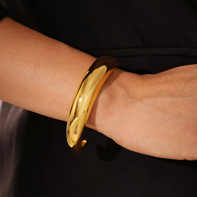 Gold polished C-shape open cuff worn on wrist