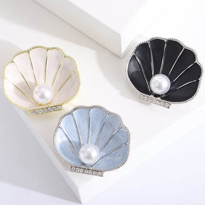 Ivory Shell, Black Shell, Blue Shell brooch styles arranged on a light display