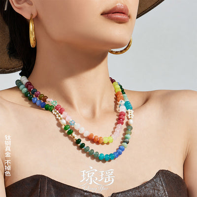 Model wearing layered colorful stone and pearl beaded necklaces