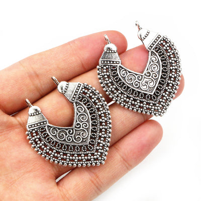 Hand held view of the ornate fan shaped pendants showing the front shape and finish