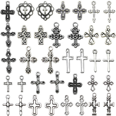 Antique silver cross charms arranged on a light background