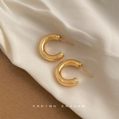 Gold thick smooth C half hoop studs on cream fabric