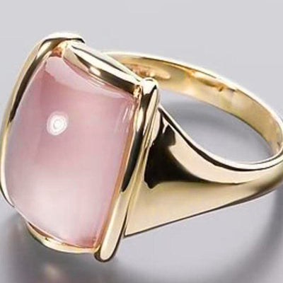 Gold ring with large rectangular pink cabochon on gray background