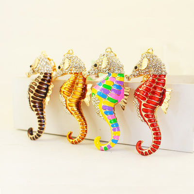 Four seahorse pendants in dark brown, gold, multicolor, and red standing together.