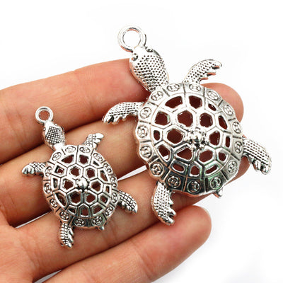 Grouped front view of openwork turtle shaped metal charms in two pictured sizes