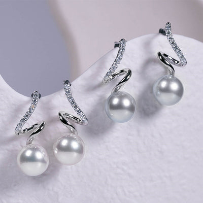 Two pairs of silver spiral pearl studs on white curved display