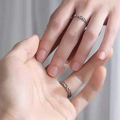 Couple hands wearing silver chain link open rings