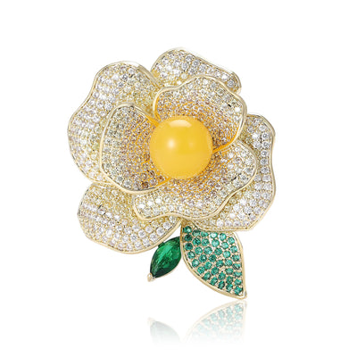 Front product view of the layered gold-tone camellia covered in clear crystals with a yellow center brooch