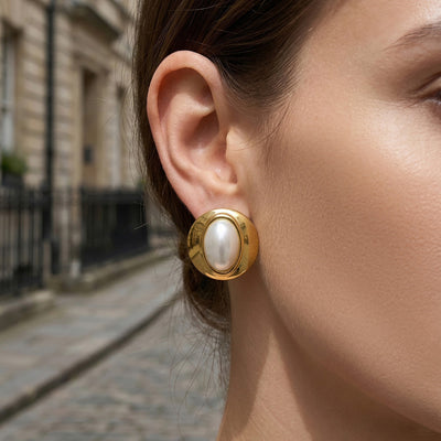Gold oval pearl-look stud earring worn street portrait