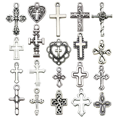 Antique silver cross and heart charms arranged on a light background