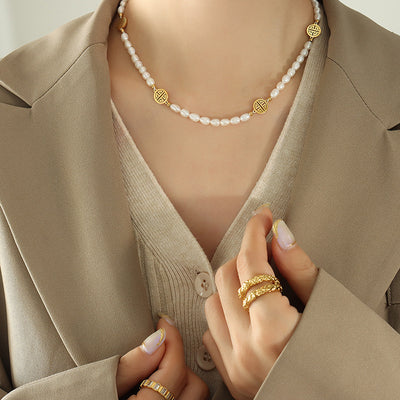 Model in beige blazer wearing pearl necklace with gold Fu discs
