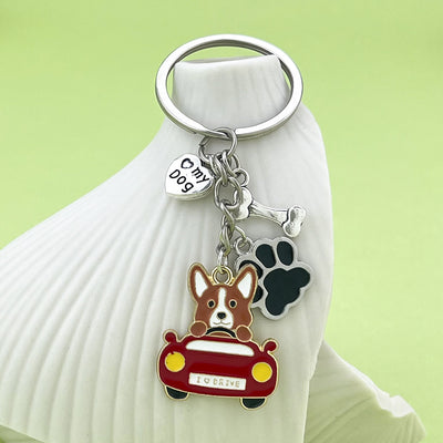 A driving corgi keychain hangs from a white display against a green background.