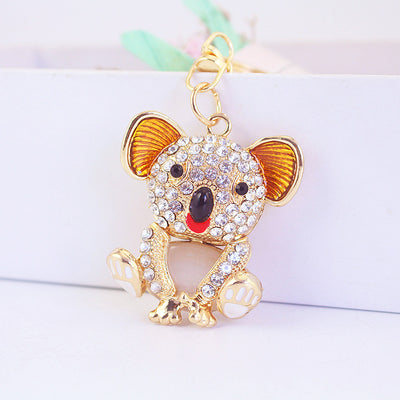 Close-up of a seated gold-tone koala keychain with a rhinestone face and pink belly.