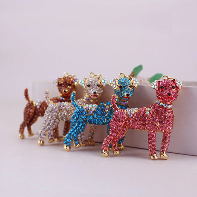 Four rhinestone dog charms in pink, blue, white, and brown arranged together.