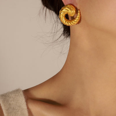 Gold twisted spiral C-shape earring worn on an ear in profile