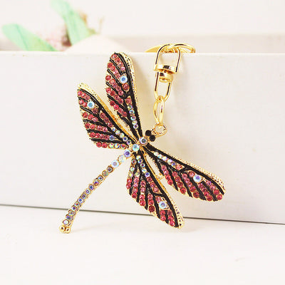 Pink rhinestone dragonfly keychain hanging against a white display block.