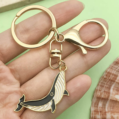 Image 1 showing a hand holding a dolphin keychain.