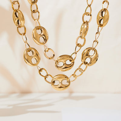 Gold hollow coffee bean oval links necklace close-up on cream background