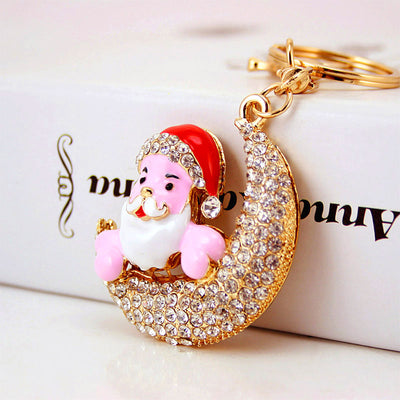 Angled close-up of the Santa and crescent charm resting against a printed box.