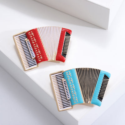 Front view of the enamel accordion brooch with gold tone keyboard decorative clothing pin on a white background