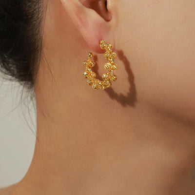 Gold twisted-bead C-hoop earring worn on model ear side view