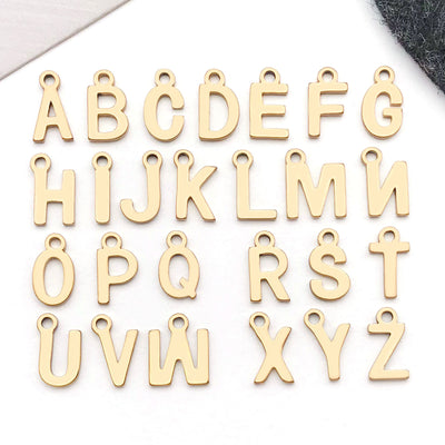Gold-tone alphabet letter charms arranged on a light background