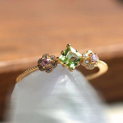 Gold ring square green stone pink flower clusters on white rock