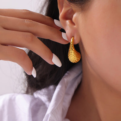 Model wearing gold hammered dimple teardrop earring