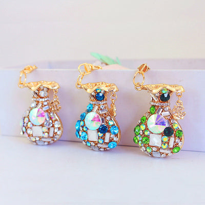 Three gold-tone money bag charms with white, blue, and green faceted stone designs.
