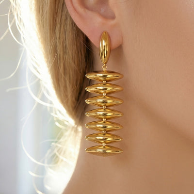 On-ear view of stacked polished disc drop earrings in main image 1.