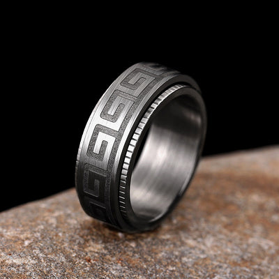 Gunmetal Greek key spinner ring standing on rough stone