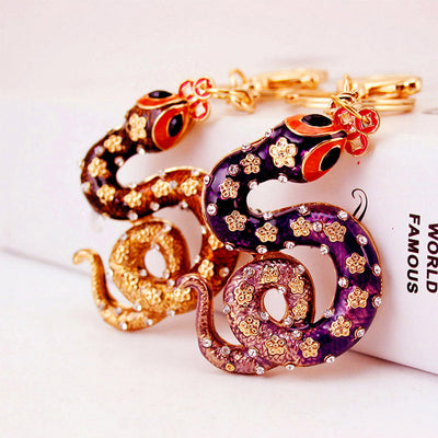 Purple and brown curled snake keychains rest side by side on a white surface.