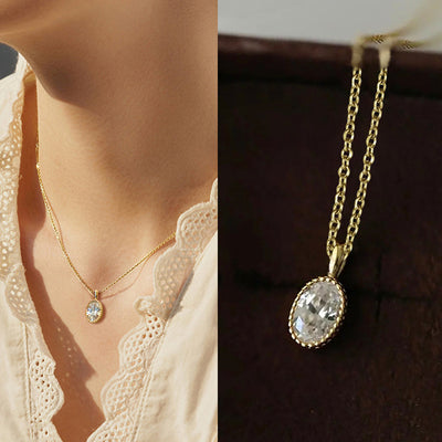 Gold oval CZ pendant necklace worn on model and close-up on dark box